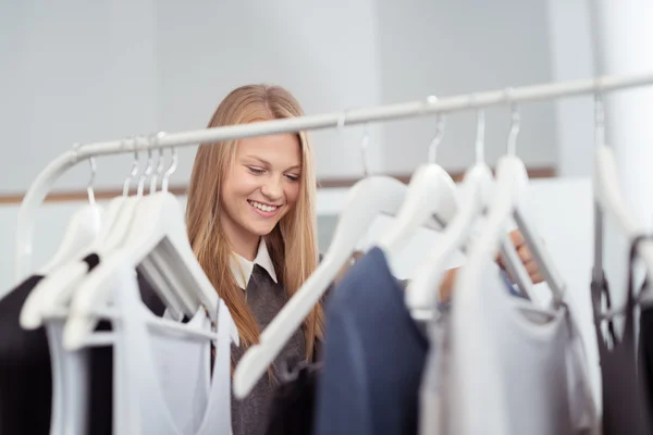 Glückliche blonde Frau auf der Suche nach Kleidung in einem Geschäft — Stockfoto