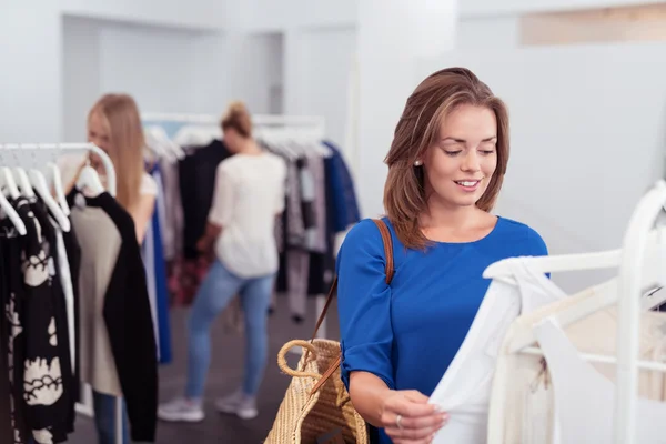 Mujer joven revisando la calidad de la camisa en la tienda —  Fotos de Stock