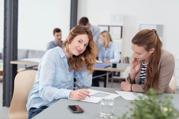 Kantoormedewerker die naar de camera kijkt tijdens een vergadering — Stockfoto