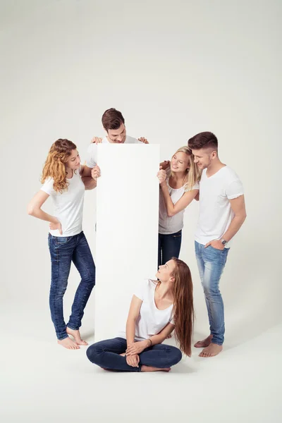 Молодые друзья с пустой белой доской по вертикали — стоковое фото