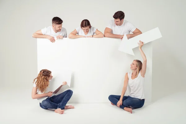 Freunde schauen und zeigen auf ein leeres weißes Plakat — Stockfoto