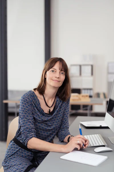 Přátelská žena, která sedí u jejího stolu — Stock fotografie