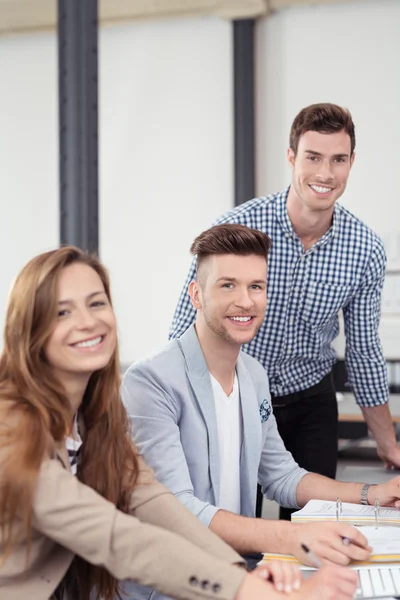 Три молодых сотрудника офиса улыбаются перед камерой — стоковое фото