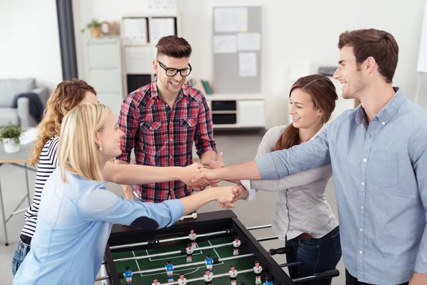 Workmates Holding their Hands Over Soccer Table — Zdjęcie stockowe