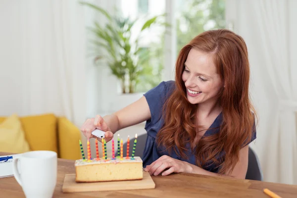 Hübsche Frau zündet die Kerzen auf einer Torte an — Stockfoto