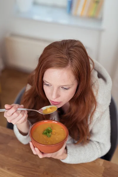 Задумчивая женщина ест суп на тарелке за столом — стоковое фото
