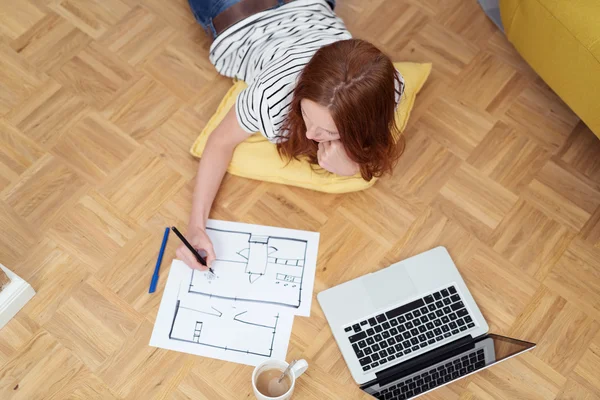 Frau auf dem Boden liegend beim Gestalten auf Papier — Stockfoto