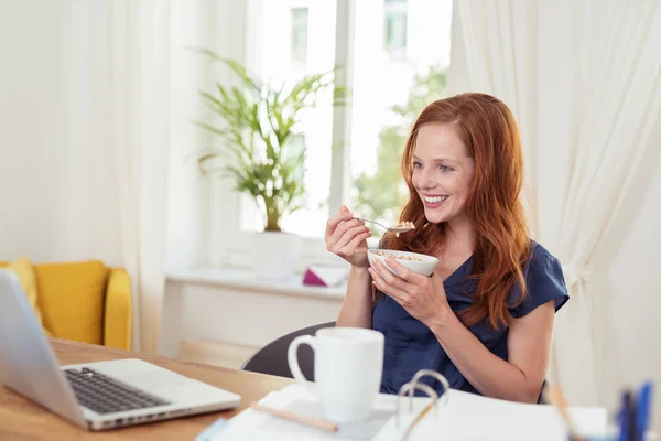 Woman eating breakfast and catching up on news — Stockfoto