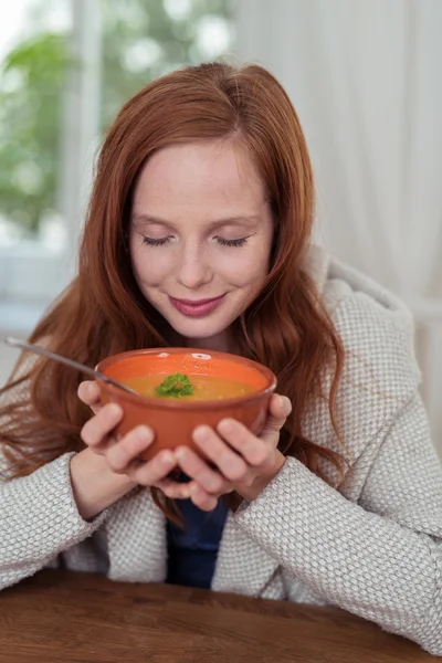 Bella giovane donna odora la sua zuppa calda — Foto Stock