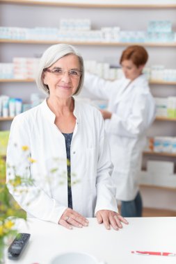 Elderly woman pharmacist in her pharmacy clipart