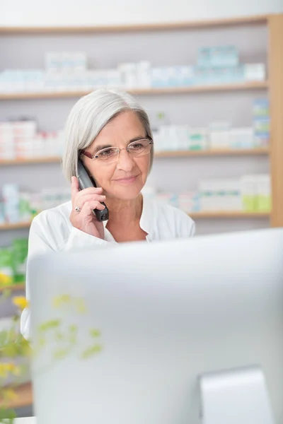 Senior pharmacist assisting a patient on the phone — Stock fotografie