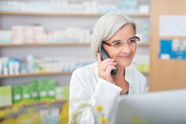 Pharmacist smiling as she takes a phone call — Stock fotografie