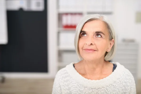 Femme de bureau senior réfléchie levant les yeux — Photo