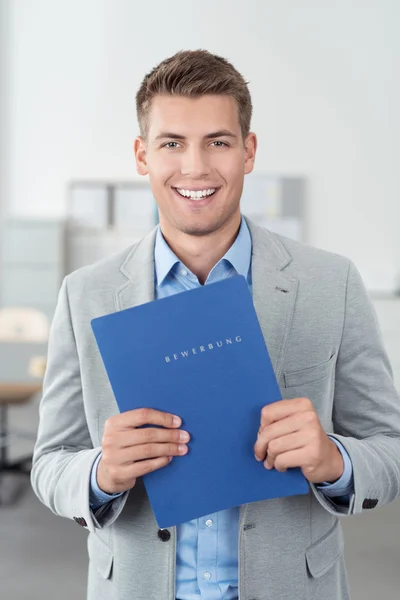 Joven empresario alegre sosteniendo archivos en la carpeta —  Fotos de Stock