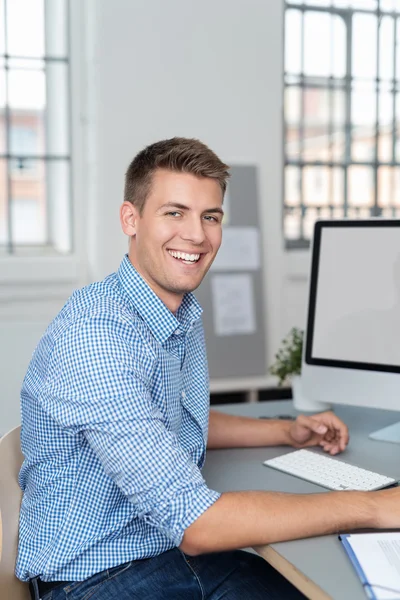 Счастливый молодой человек на работе в офисе — стоковое фото