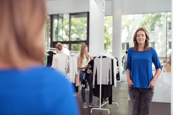 Frau im Geschäft blickt ihr Spiegelbild an — Stockfoto