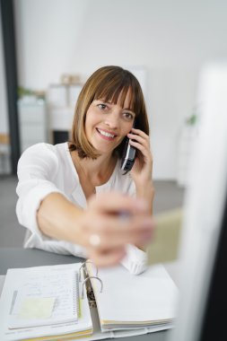 Businesswoman on Phone Putting Note on Computer clipart