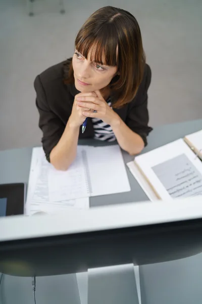 Fundersam affärskvinna sitter vid hennes skrivbord — Stockfoto