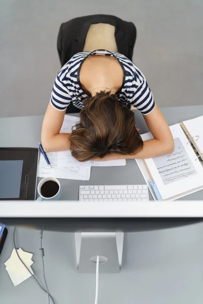 Unavený úřad žena naklání hlavu na stůl — Stock fotografie
