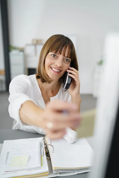 Empresária no telefone colocando nota no computador — Fotografia de Stock