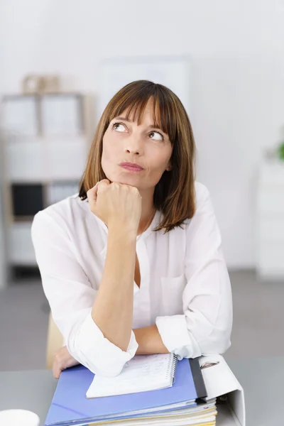 Nachdenkliche Geschäftsfrau lehnt an ihrem Schreibtisch — Stockfoto