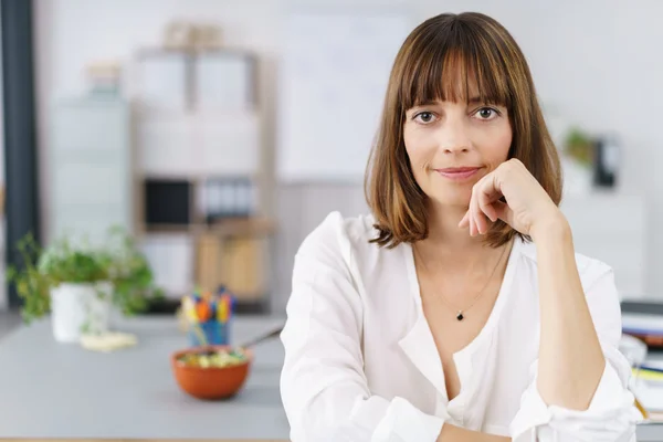 Büroangestellte am Schreibtisch blickt in die Kamera — Stockfoto