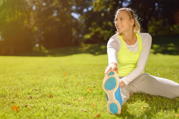 Glücklich fitte Frau streckt ihre Beine im Park — Stockfoto