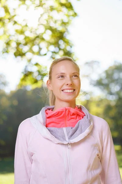 Glückliche Frau lächelt im Park in die Ferne — Stockfoto