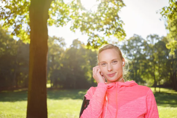 Donna sorridente con auricolare al parco — Foto Stock