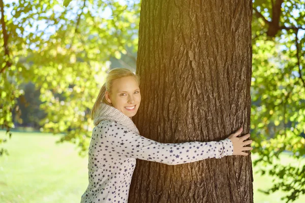 Jolie femme étreignant un tronc d'arbre au parc — Photo