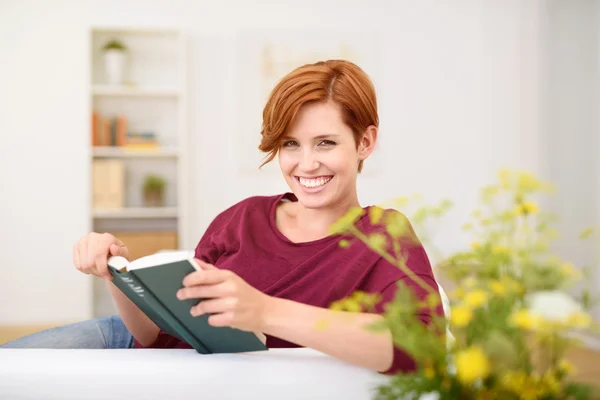Glückliche Frau mit Buch lächelt in die Kamera — Stockfoto
