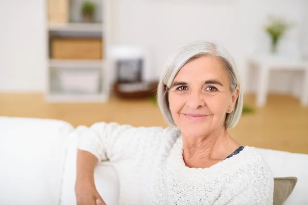 Lächelnde Seniorin entspannt auf der Couch — Stockfoto