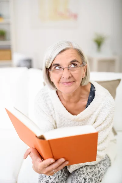 Nachdenkliche Seniorin mit Buch in der Hand — Stockfoto