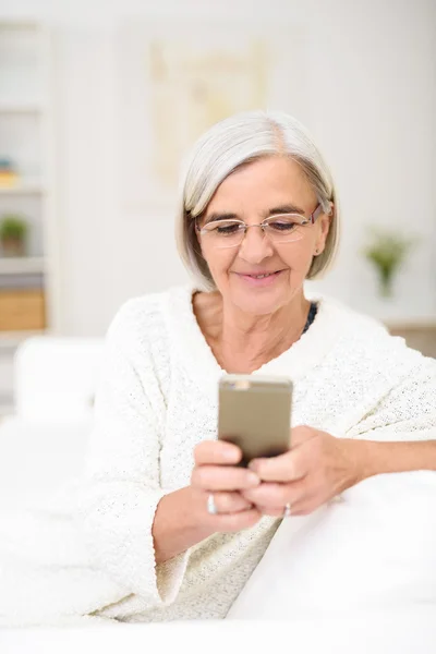 Frau mittleren Alters telefoniert auf der Couch — Stockfoto
