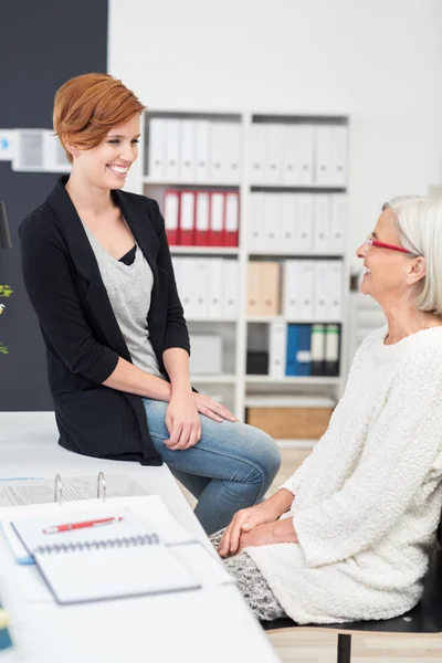 Två glada Office kvinnor chattar vid bordet — Stockfoto