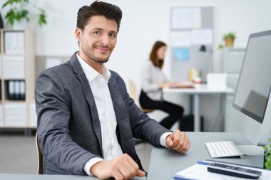 manager sitting at desk and working on computer clipart