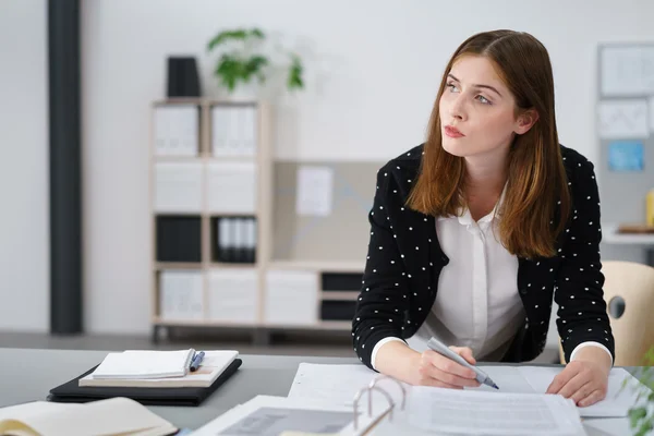 Nachdenkliche Geschäftsfrau arbeitet an Dokumenten auf dem Schreibtisch — Stockfoto