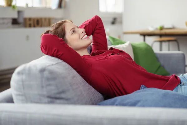 Розслаблена жінка відпочиває на своєму дивані — стокове фото