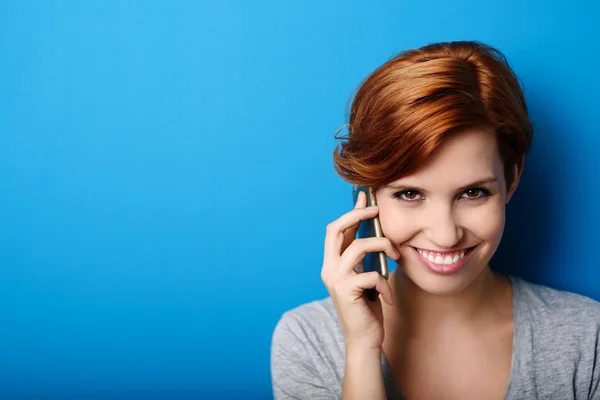 Mujer llamando por teléfono contra la pared azul — Foto de Stock