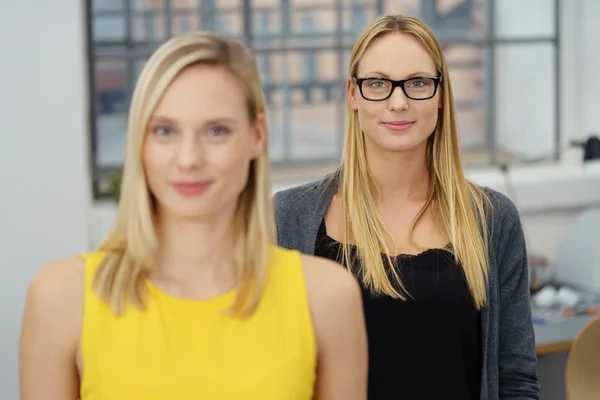 Bürofrau hinter ihrem Kollegen lächelt — Stockfoto