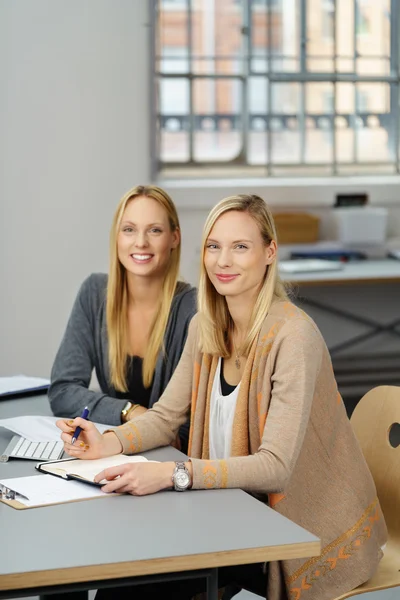 Zwei hübsche Bürofrauen sitzen am Tisch — Stockfoto