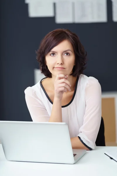 Женщина из созерцательного офиса за столом с ноутбуком — стоковое фото