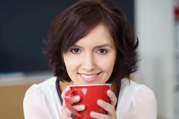 Sorrindo escritório mulher segurando uma xícara de bebida quente — Fotografia de Stock