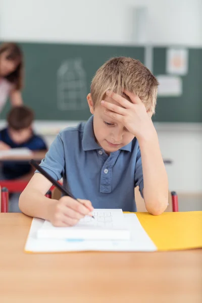 Young boy working on his class notes at school — Stok fotoğraf