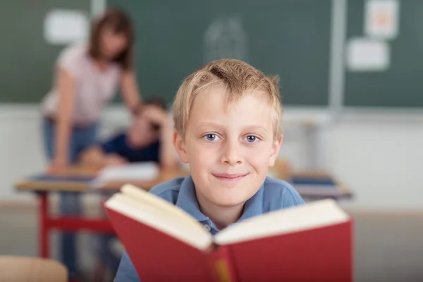 Sorridente giovane ragazzo con un grande libro di testo — Foto Stock