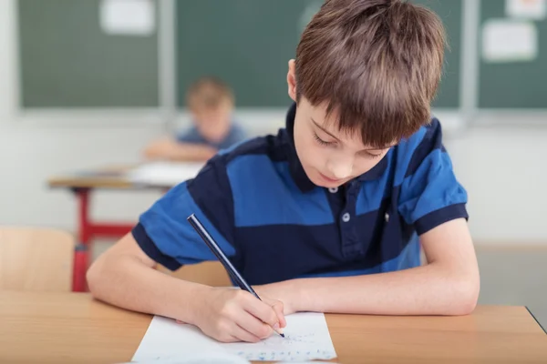 Young boy taking notes in class at school — Stockfoto