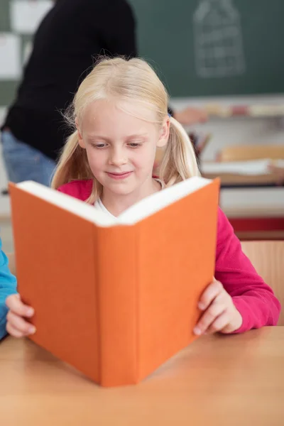 Маленькая девочка читает в классе — стоковое фото