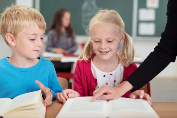 Teacher helping a cute young girl at school — Stock Photo, Image