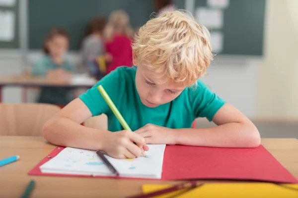 Young blond boy hard at work at school — Stockfoto