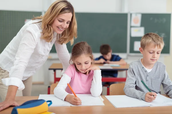 Lächelnder Lehrer bei der Überprüfung einer kleinen Mädchenarbeit — Stockfoto